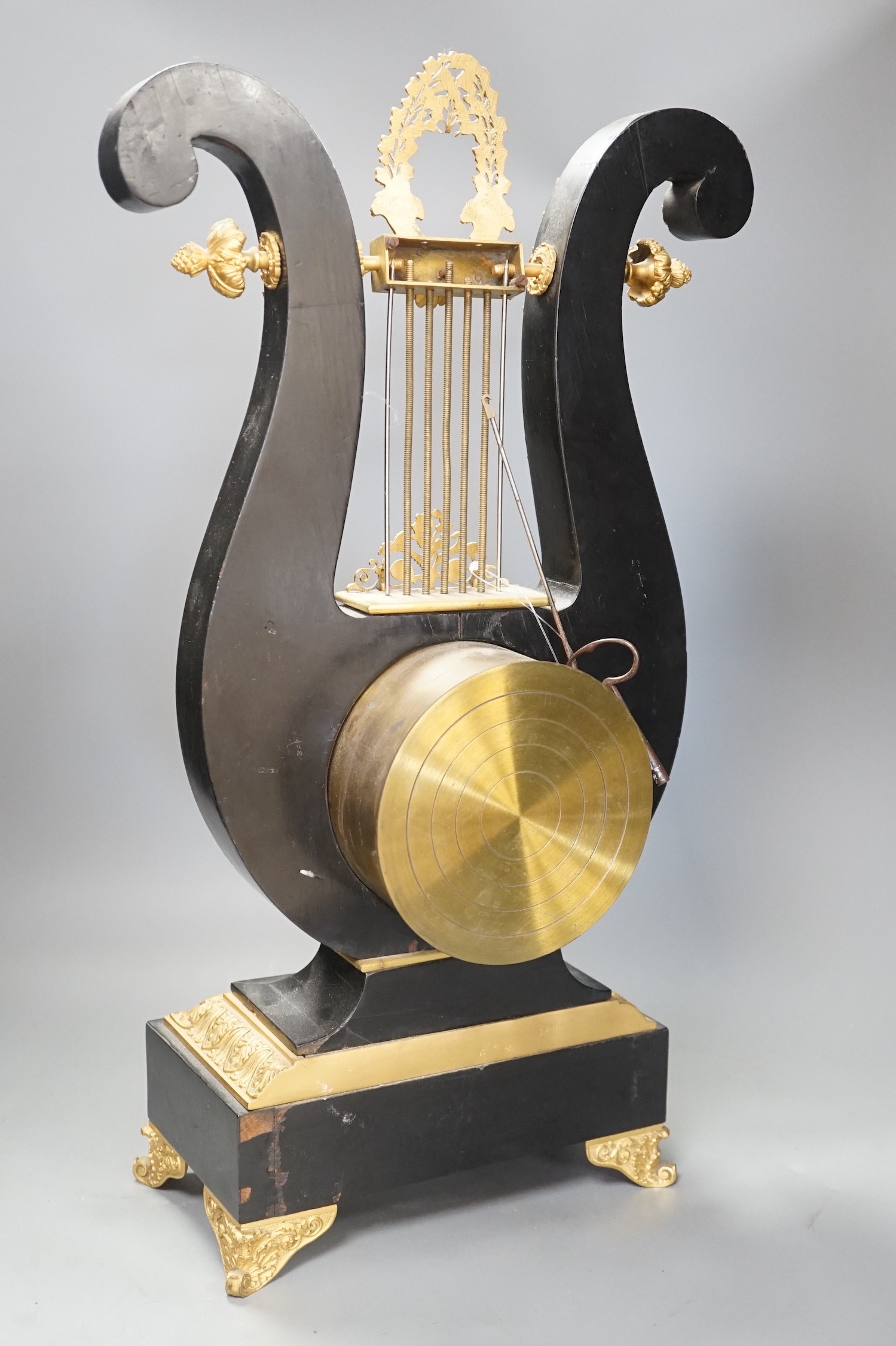 A 19th century French black lyre shaped clock, with gilt leaf decoration on scroll feet, 57cm tall